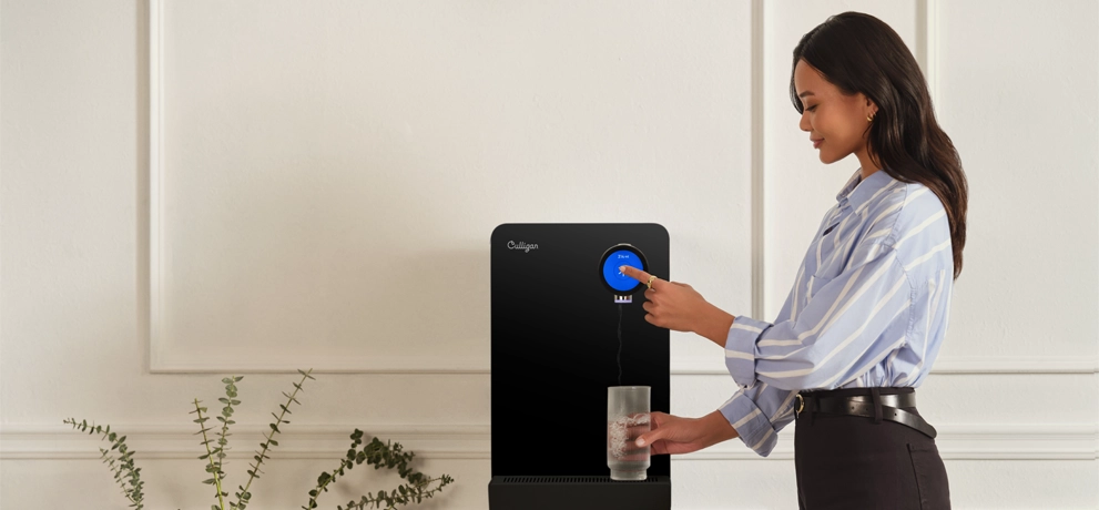 Mulher serve-se de uma máquina dispensadora de água Culligan Purity 