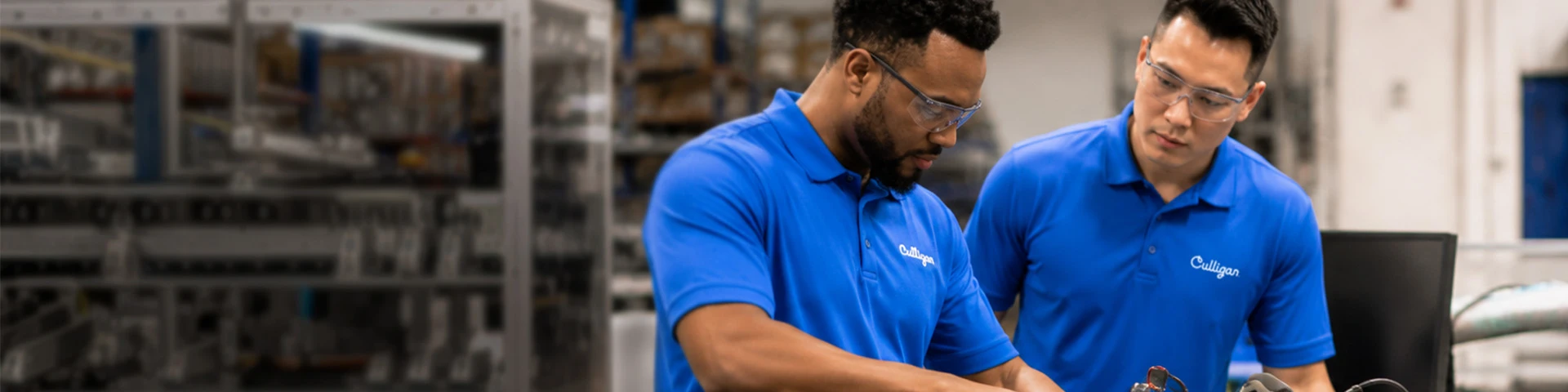 Dois técnicos de manutenção Culligan efetuam reparações, nos armazéns da empresa.